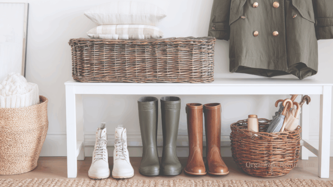Minimal entryway with woven baskets, rain boots, and a neatly folded coat in soft natural light.